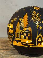 Detail winterdorp op verlichte zwarte kerstbol